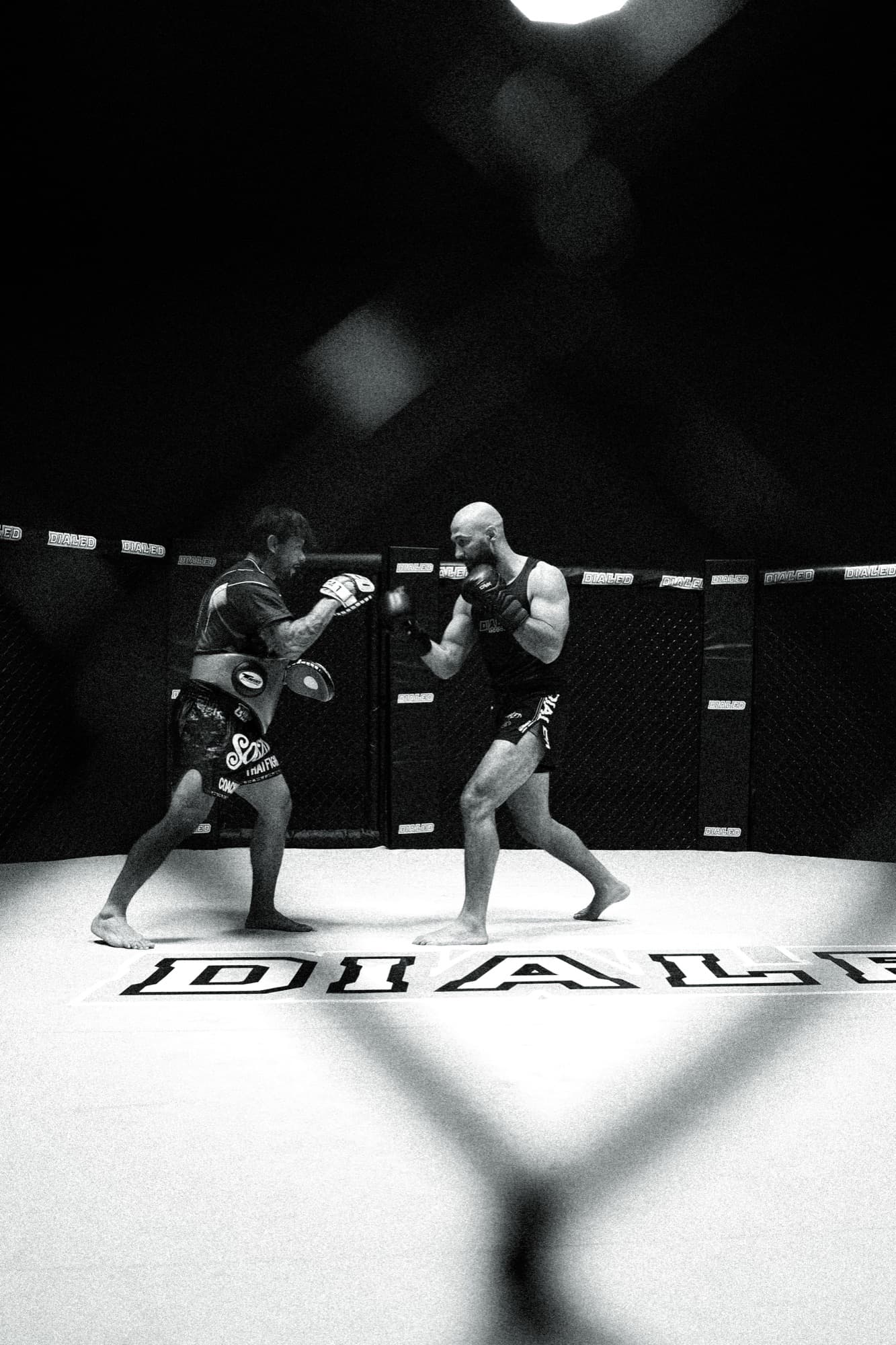 Coach holding pads for a fighter on the gym floor